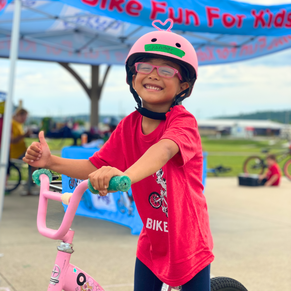 Smiling child giving thumbs up in Pedal Kids Learn To Pedal camp