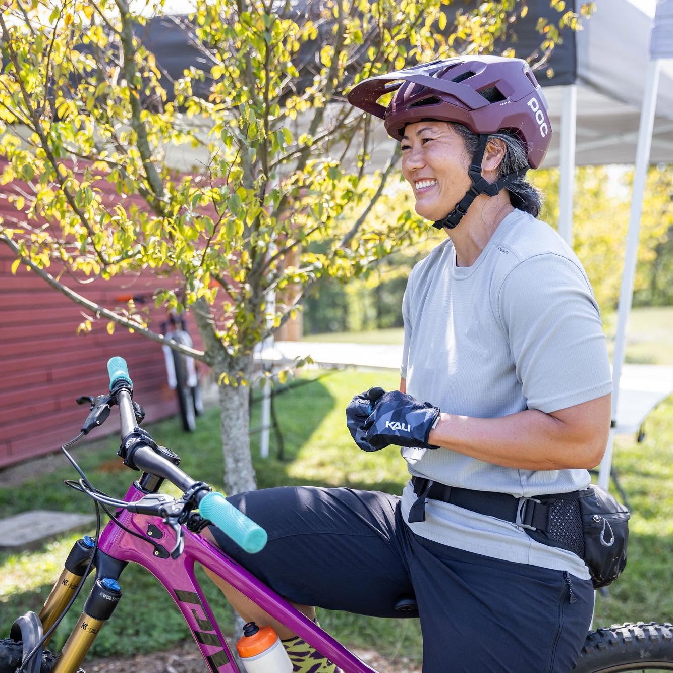 Coach Sarah smiling beside her mountain bike
